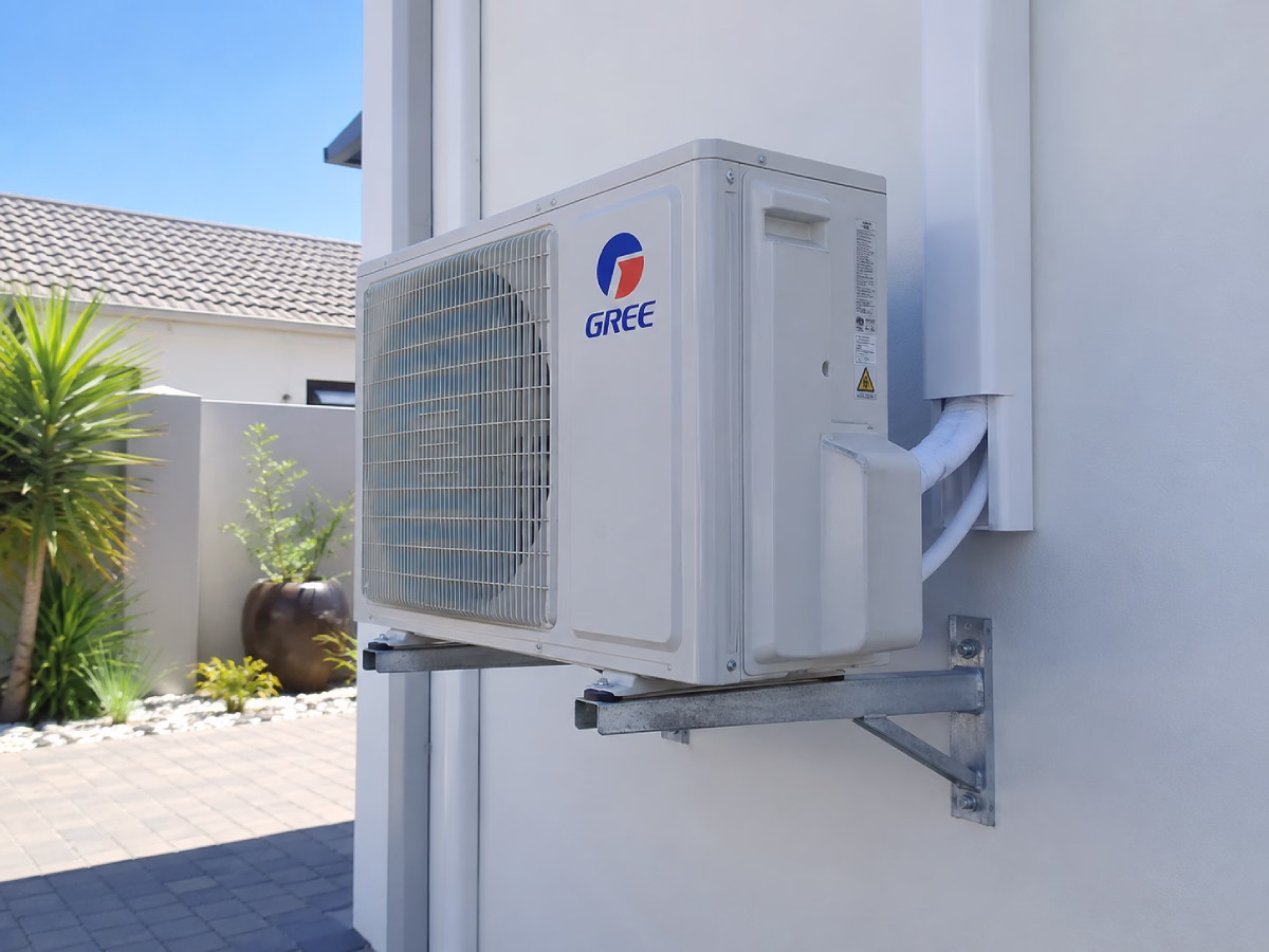 Outdoor condenser unit mounted on wall brackets, raised clear of the paving below